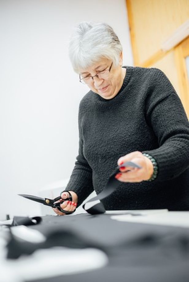 Eine Näherin schneidet Stoff in der Vilber's-Werkstatt zu