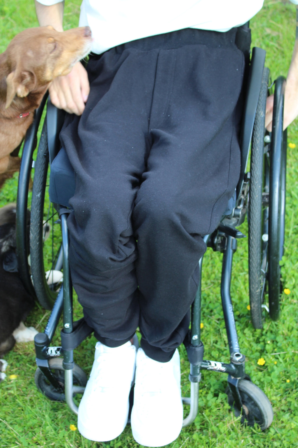 Close-up of Vilber's adaptive joggers worn in a wheelchair, showing the seated fit across the thighs and the clean front panel without bunching.