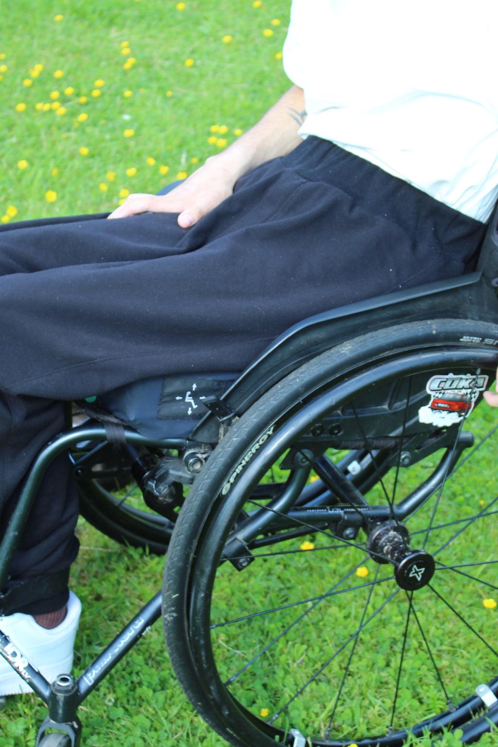 Close-up side view of Vilber's adaptive joggers showing the elasticated waistband and smooth fabric across the hip in a seated position.