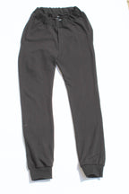 Vilber's adaptive joggers laid flat on white background, front view. Black, elasticated waistband, ribbed ankle cuffs, no pockets.