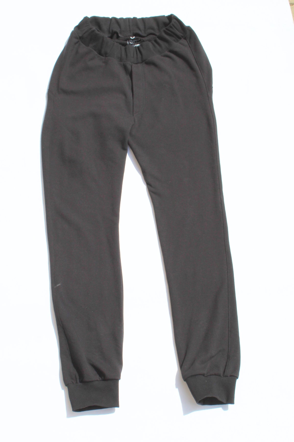 Vilber's adaptive joggers laid flat on white background, front view. Black, elasticated waistband, ribbed ankle cuffs, no pockets.
