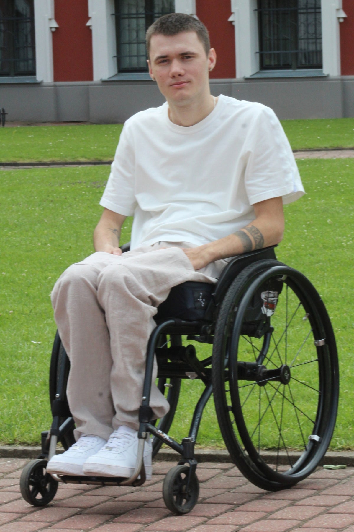 Close front view of a wheelchair user wearing Vilber's beige ramie summer trousers, showing the relaxed seated fit through the legs.